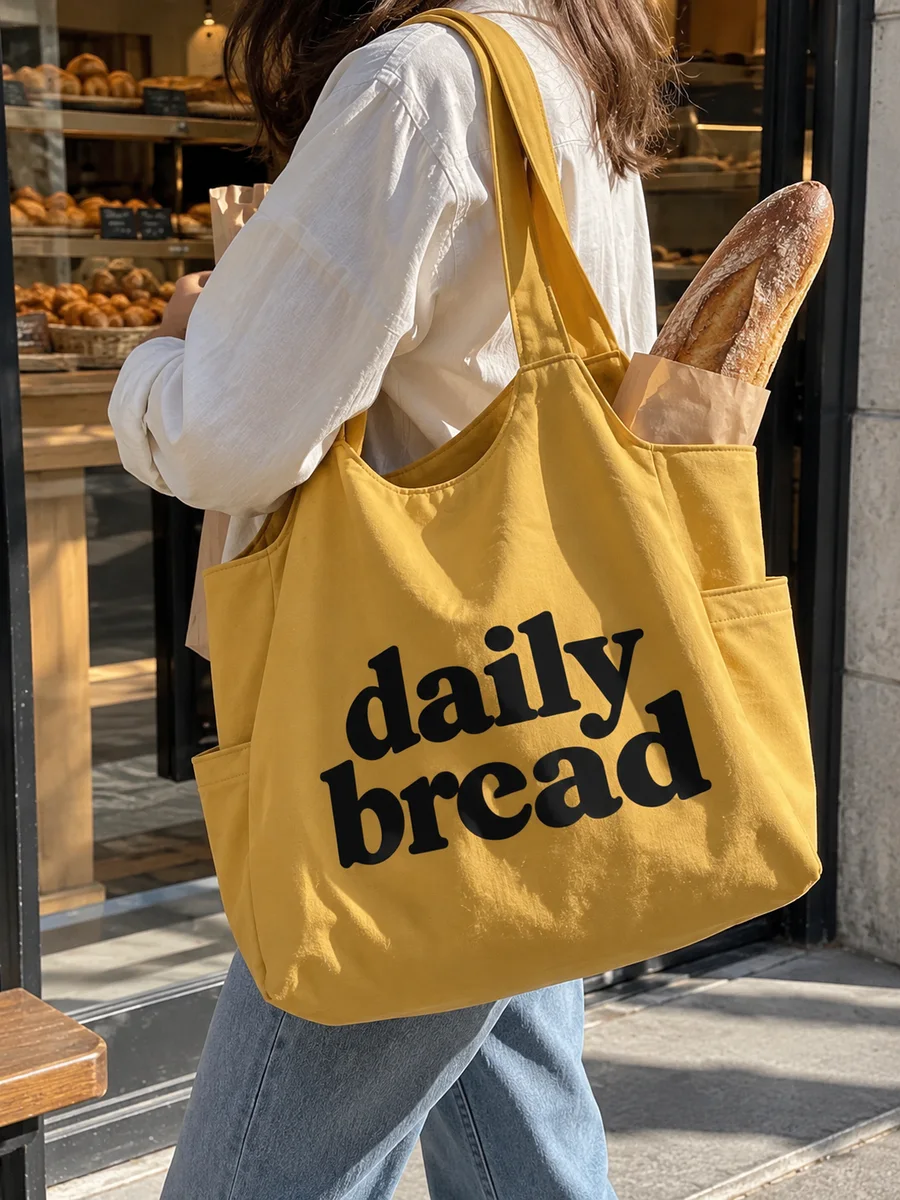 Mustard bag, black "daily bread" print, on the shoulder