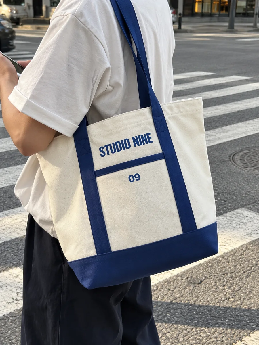 "STUDIO NINE" print, royal-blue handles and pocket binding, on the shoulder